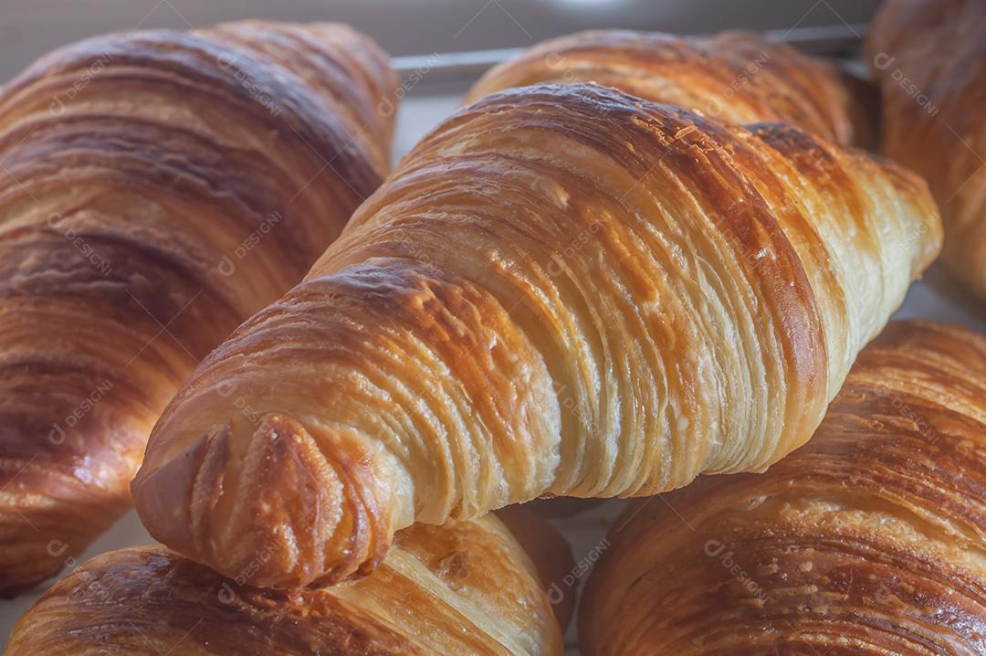 Deliciosos croissants caseiros em um papel manteiga branco, luz natural.