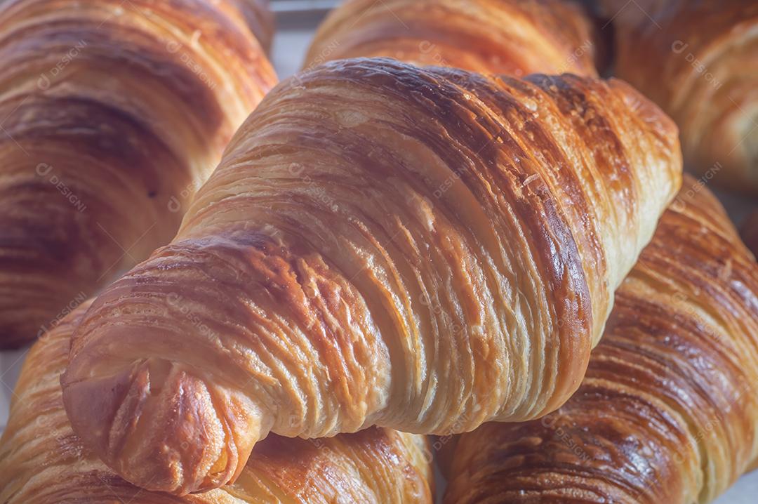 Deliciosos croissants caseiros em um papel manteiga branco, luz natural.