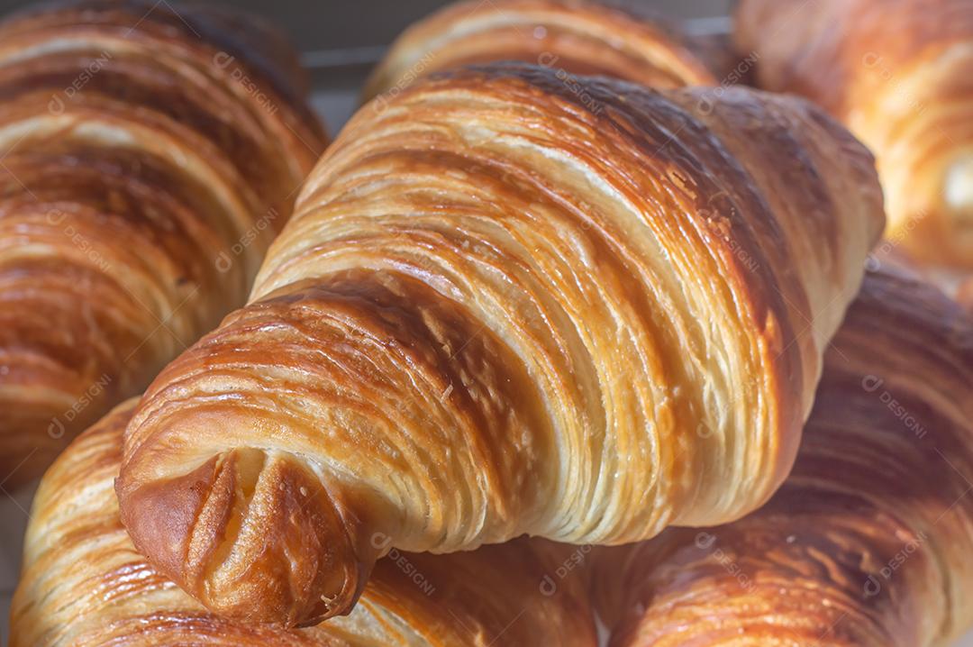 Deliciosos croissants caseiros em um papel manteiga branco, luz natural.