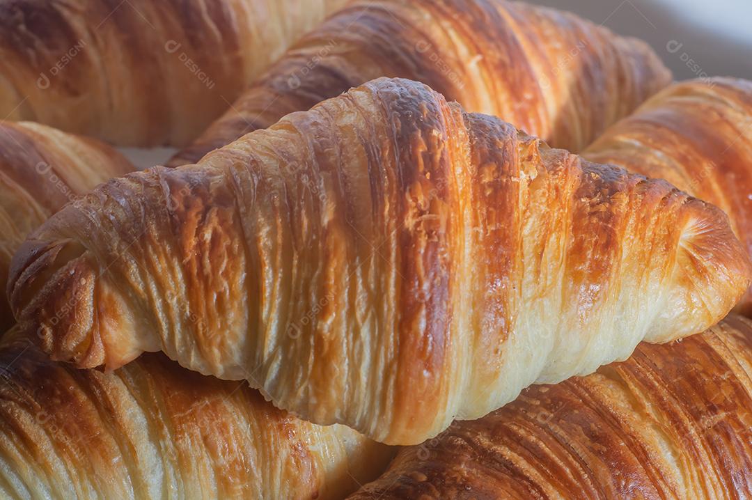 Deliciosos croissants caseiros em um papel manteiga branco, luz natural.
