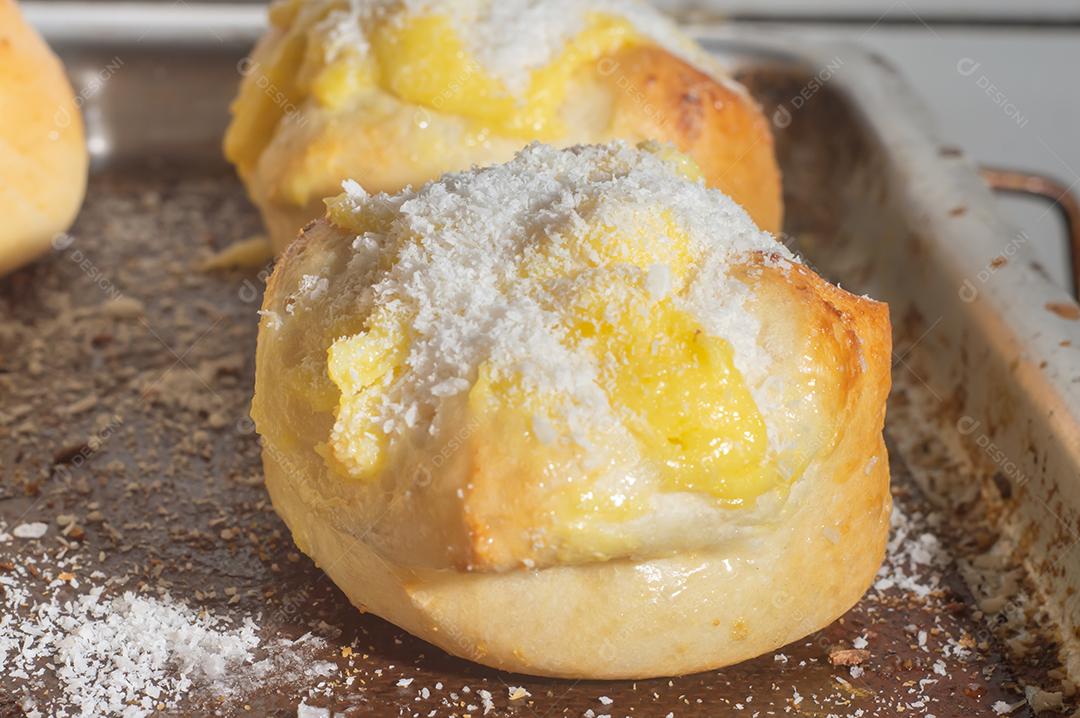 Pães caseiros de fermento fresco com recheio de creme com açúcar de confeiteiro na grade de metal preto