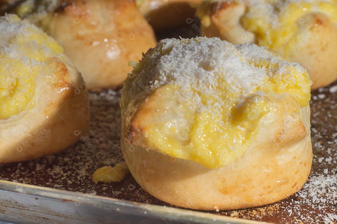 Pães caseiros de fermento fresco com recheio de creme com açúcar de confeiteiro na grade de metal preto