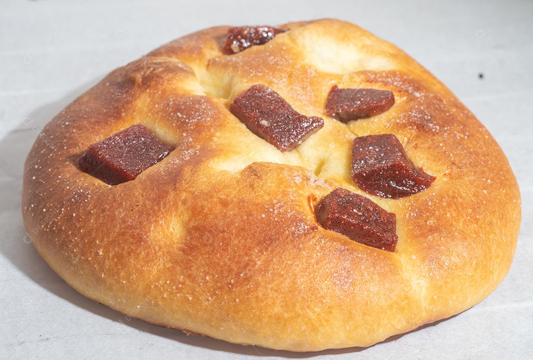 Pão doce com doce de goiaba e farinha doce em uma mesa de madeira marrom. É um tipo de pão comum no Brasil