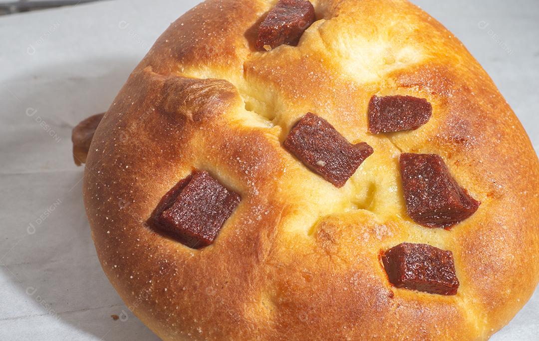 Pão doce com doce de goiaba e farinha doce em uma mesa de madeira marrom. É um tipo de pão comum no Brasil
