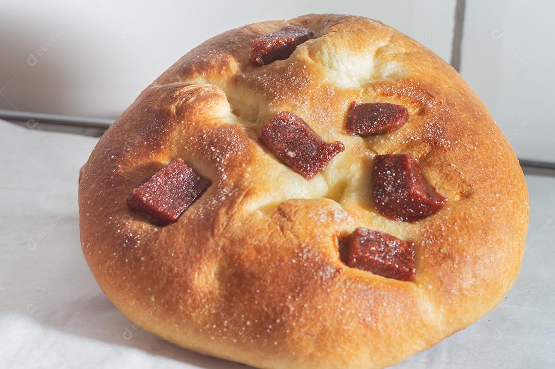 Pão doce com doce de goiaba e farinha doce em uma mesa de madeira marrom. É um tipo de pão comum no Brasil