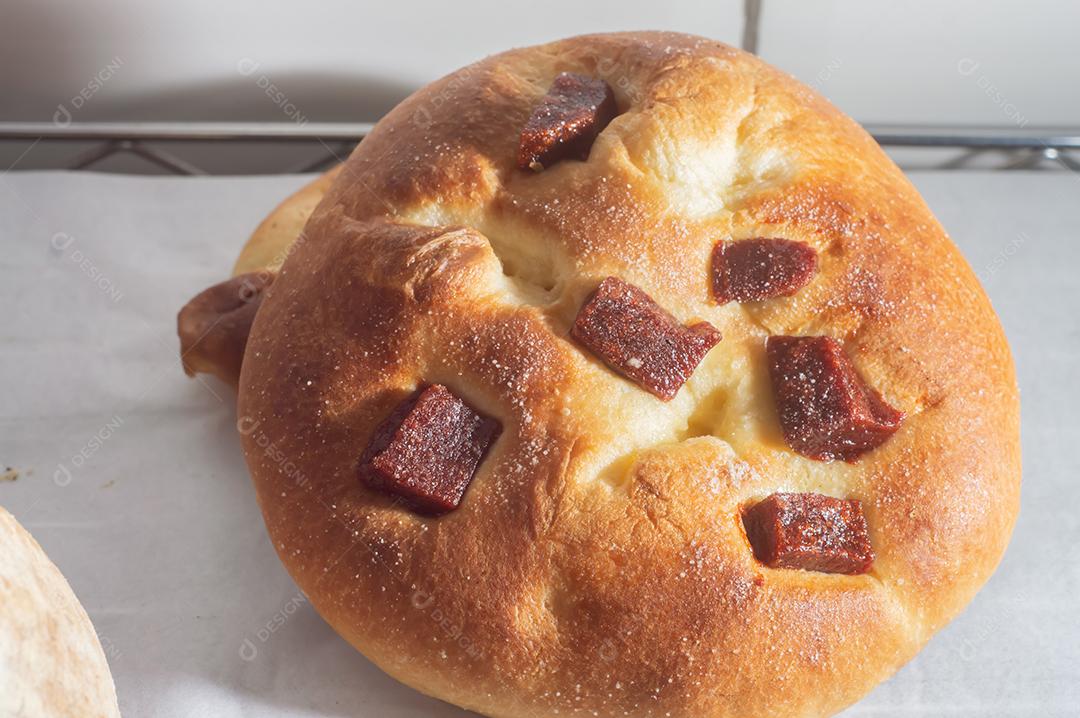 Pão doce com doce de goiaba e farinha doce em uma mesa de madeira marrom. É um tipo de pão comum no Brasil