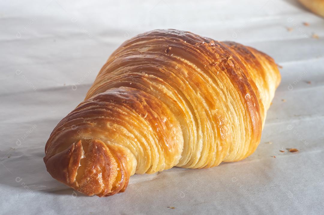 Deliciosos croissants caseiros em um papel manteiga branco, luz natural.