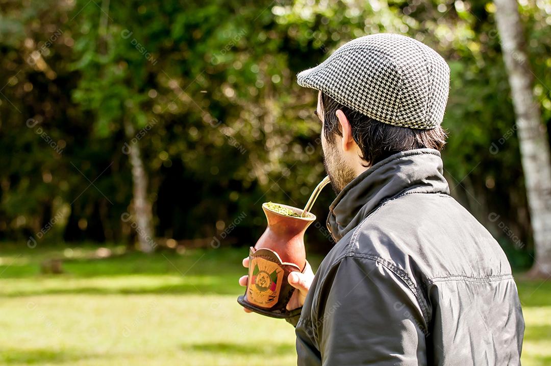 Homem gaúcho com barba e boina tomando chá mate em um dia ensolarado