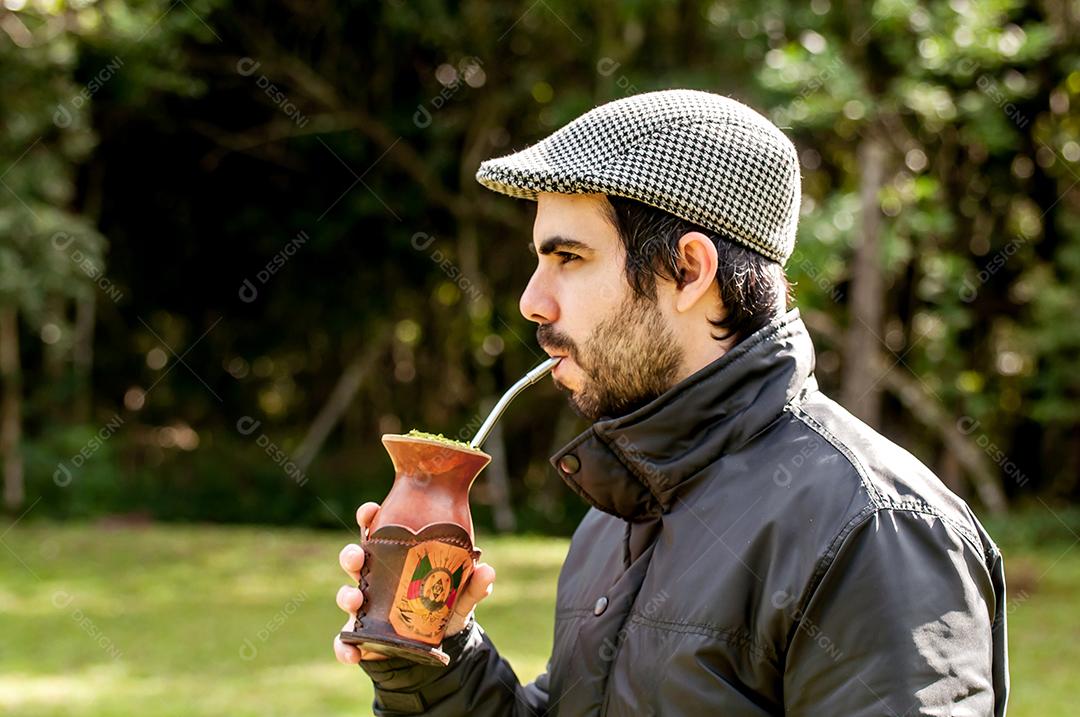 Homem gaúcho com barba e boina tomando chá mate em um dia ensolarado