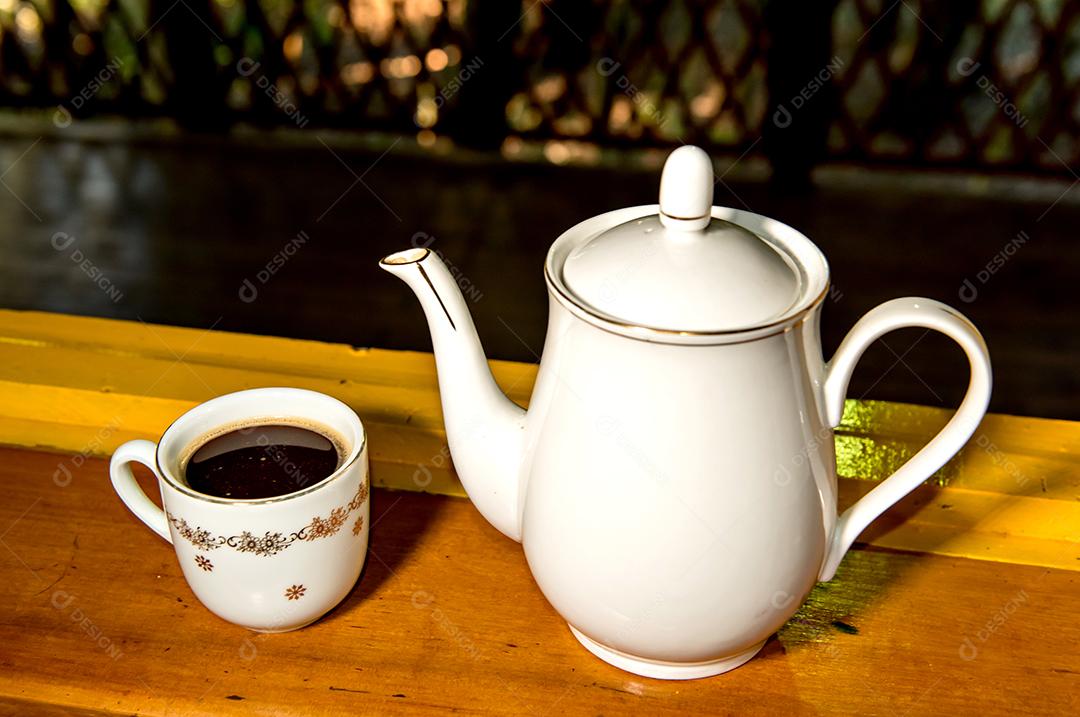 Antigo bule de café de porcelana e xícara na mesa amarela