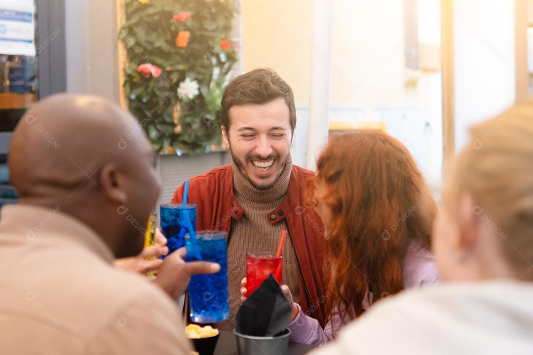 Grupo de amigos multirraciais felizes ri bebendo e comendo na reunião do restaurante - amizade multiétnica