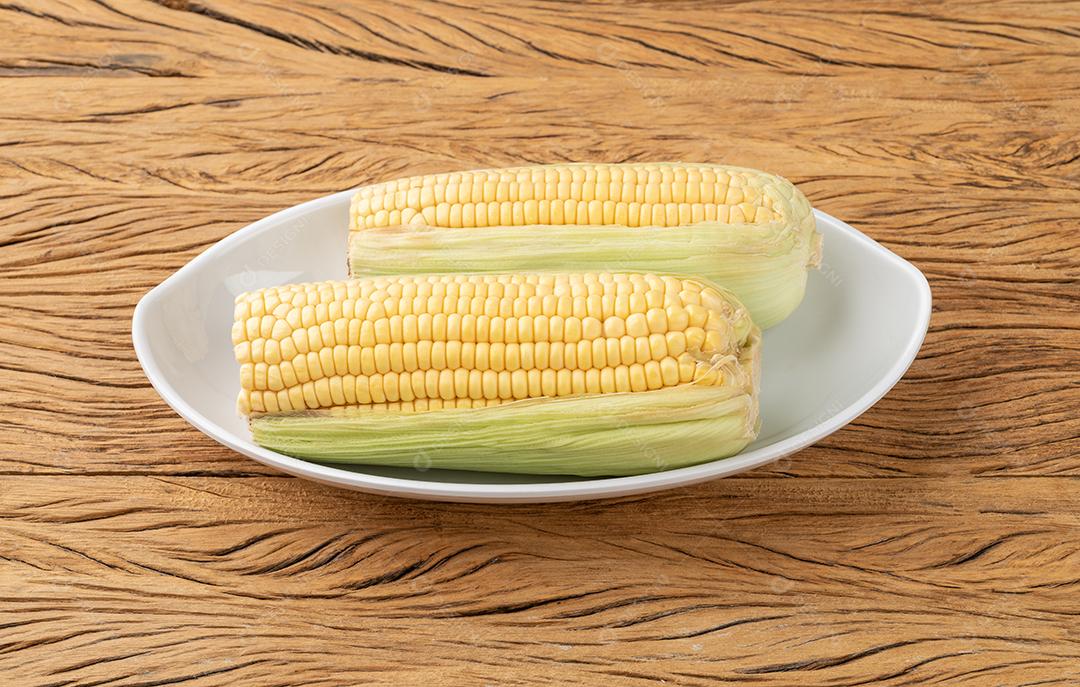 Espigas de milho em um prato sobre a mesa de madeira
