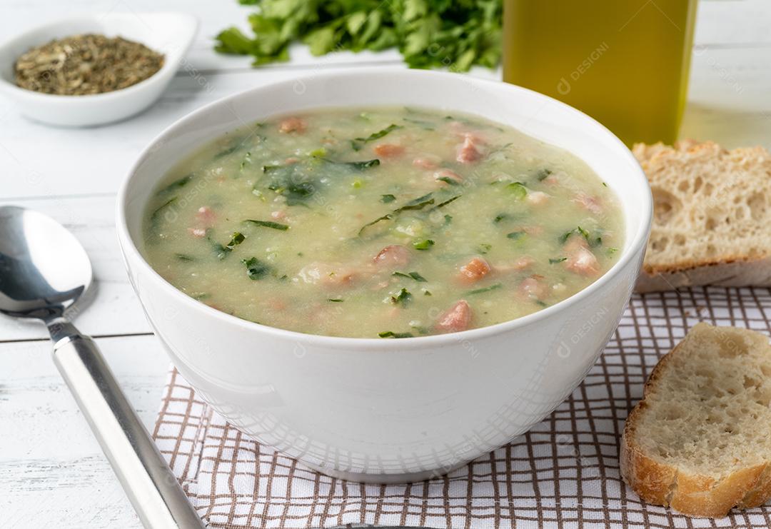 Sopa verde tradicional portuguesa com batata couve verde e salsicha numa tigela com pão