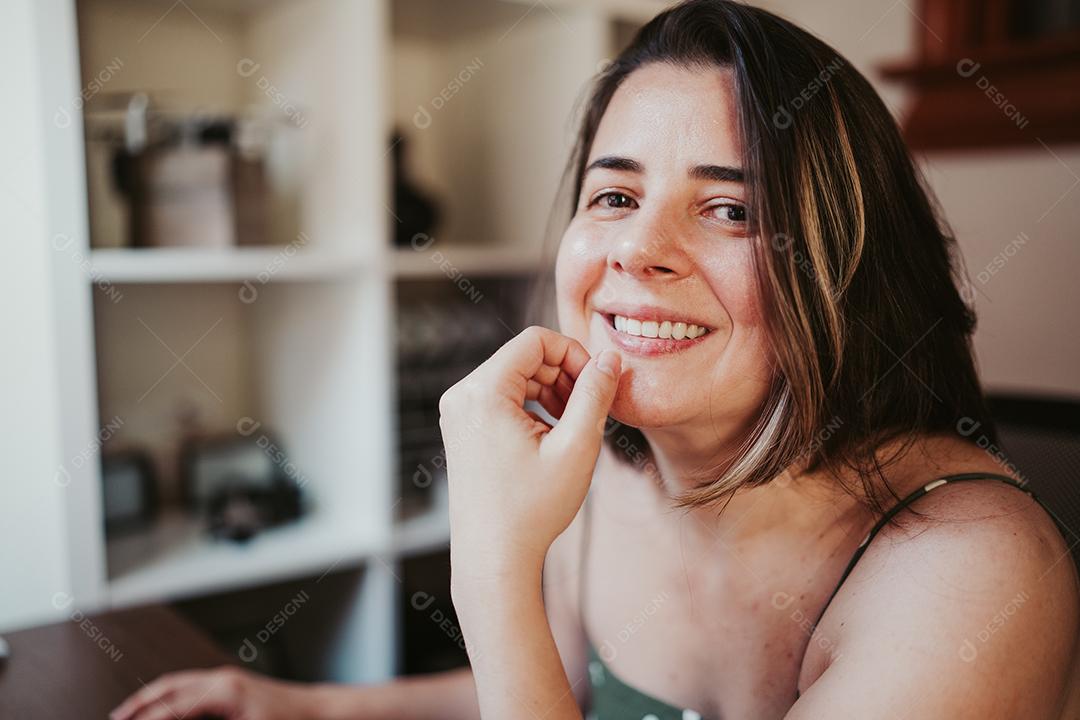 Mulher sorrindo em frente ao computador trabalhando em casa