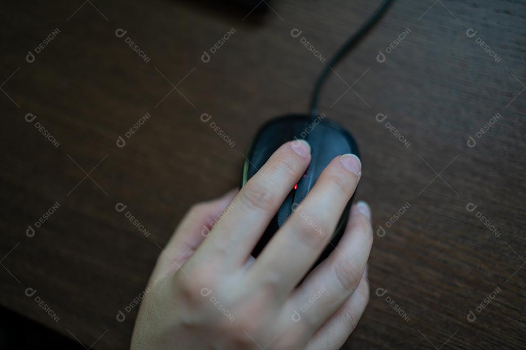 Mão segurando o mouse no escritório em casa
