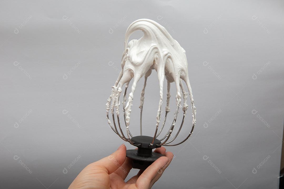 Batedor de metal com ovo batido com sombras brancas no fundo branco