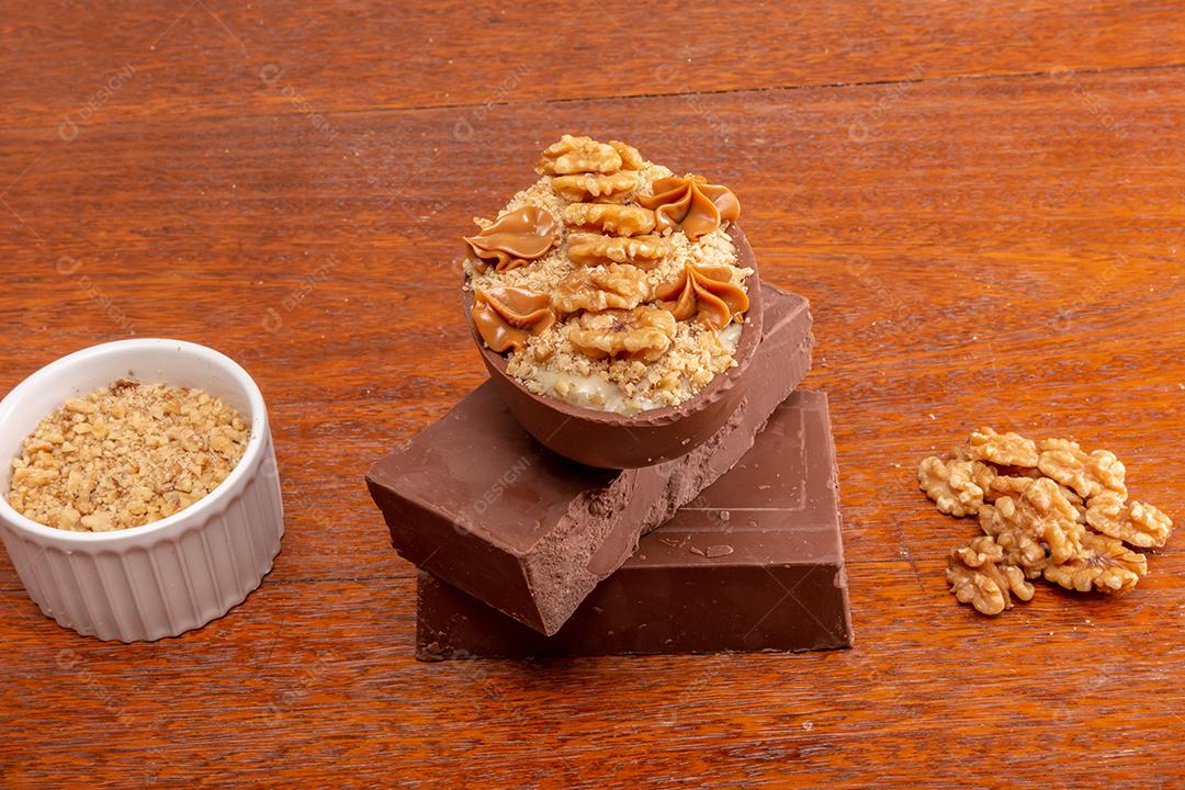 Ovo de chocolate recheado com nozes para a Páscoa no fundo do timbe