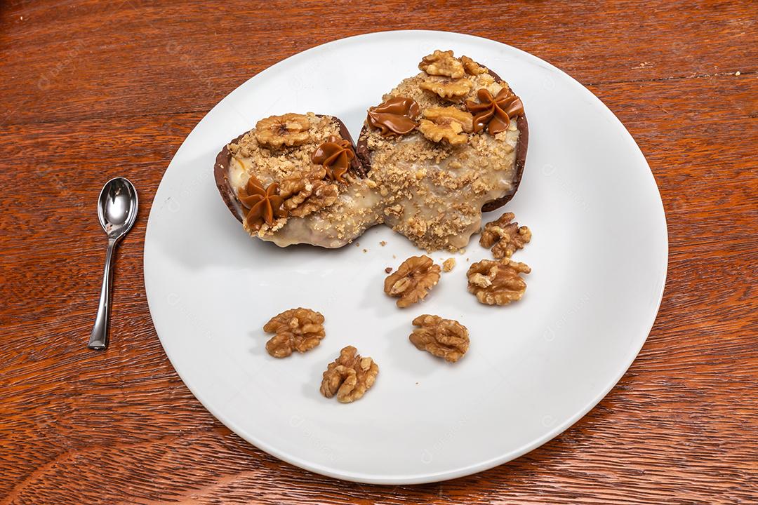 Ovo de chocolate recheado com nozes para a Páscoa no fundo do timbe