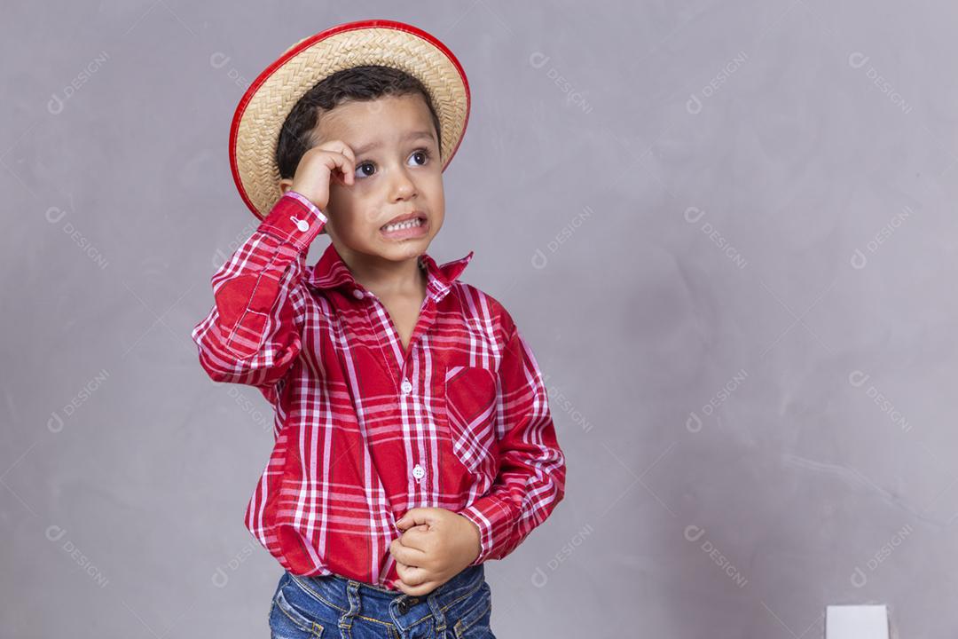 menino bonitinho vestindo roupas típicas para Festa Junina com co