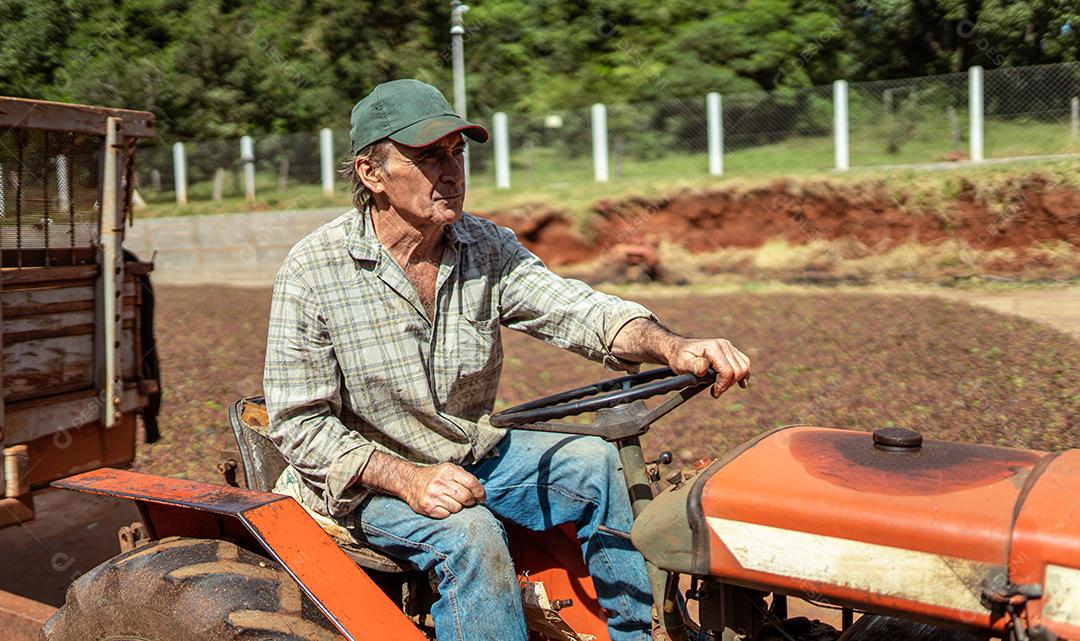 Agricultor latino com um chapéu dirigindo trator na fazenda.