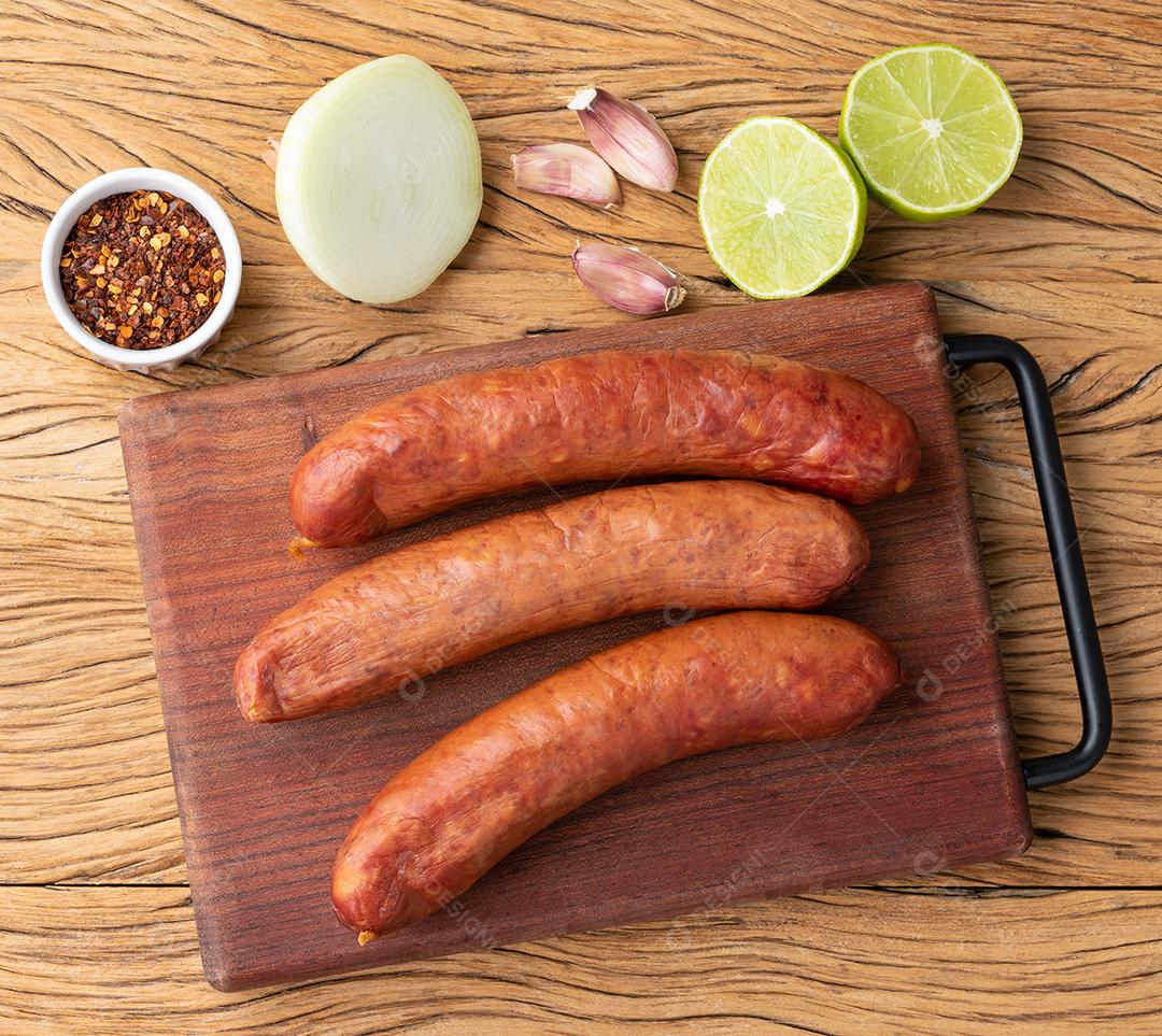 Linguiça de porco calabresa sobre tábua de madeira com temperos