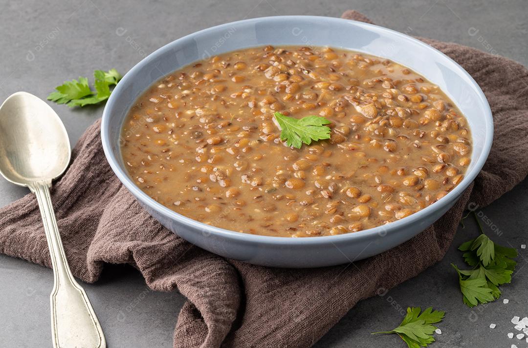 Sopa de lentilha em uma tigela com tempero sobre fundo de pedra