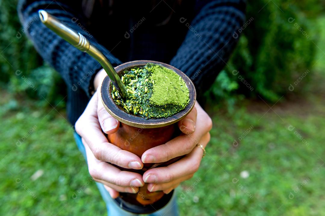 Mulher segurando um chá de erva-mate tradicional sul-americano (chimarrao no Brasil)