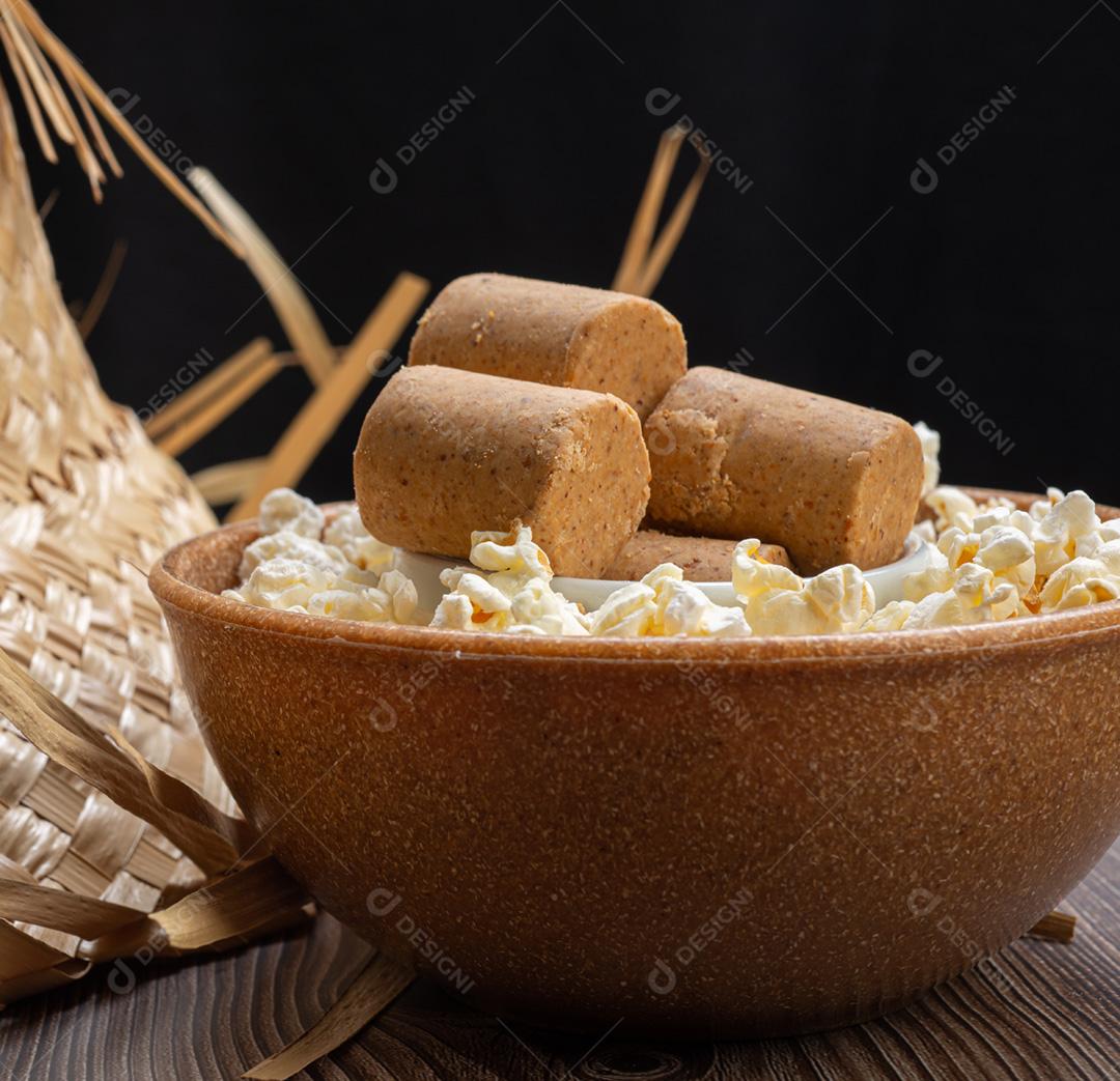 Popcorn, peanut candy served in a pot with a straw hat on a wooden table