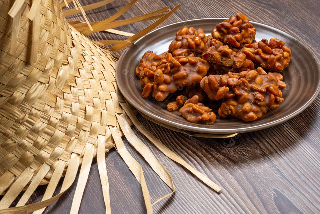 Doce de amendoim servido em prata marrom com chapéu de palha em madeira