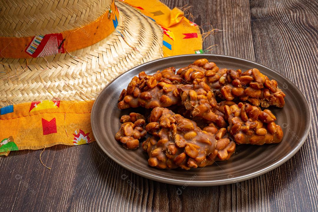 Doce de amendoim servido em prata marrom com chapéu de palha em madeira