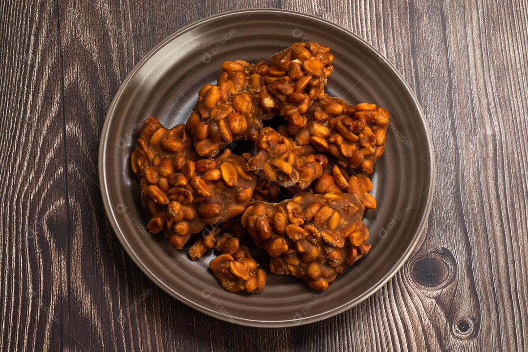 Doce de amendoim servido em prata marrom com chapéu de palha em madeira