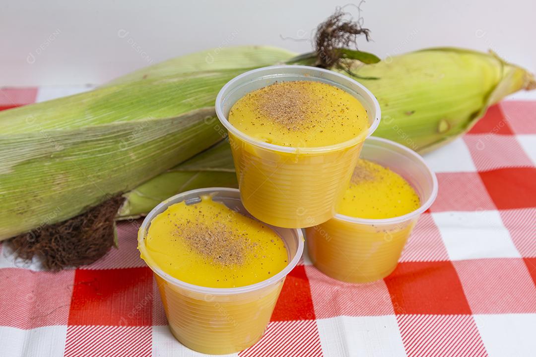 Caldo de milho e espigas de milho acima de mesa xadrez