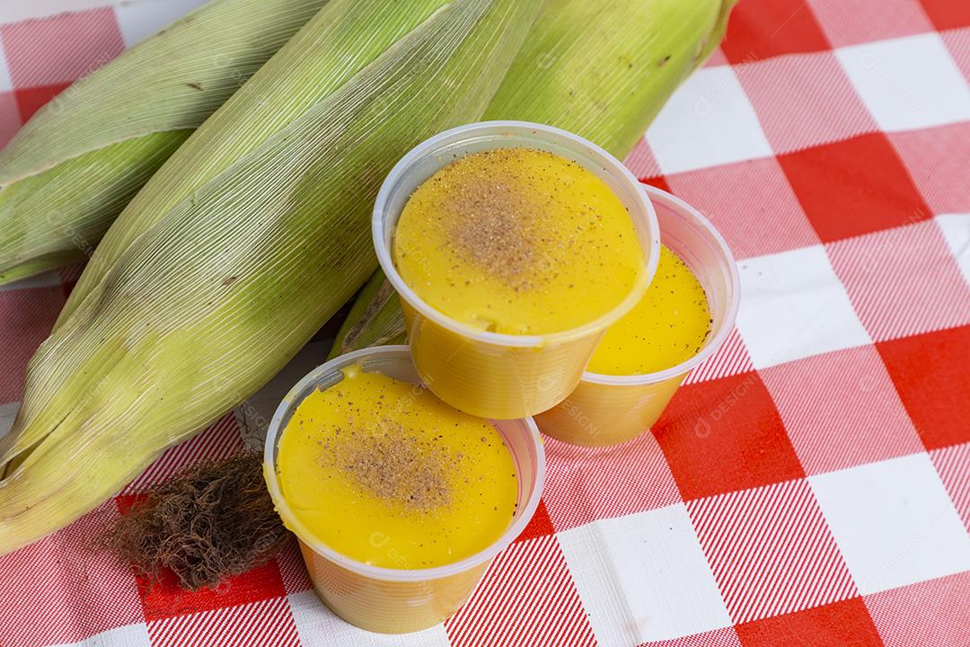 Caldo de milho e espigas de milho acima de mesa xadrez