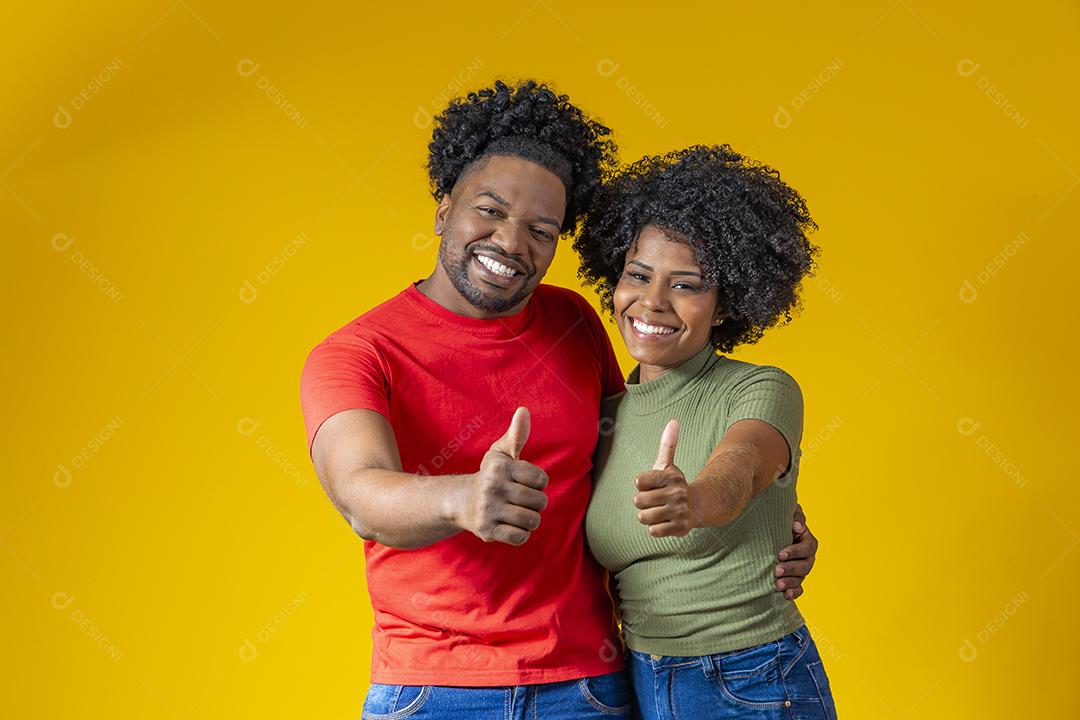 Jovem Casal Afro fazendo sinal de ok em fundo amarelo