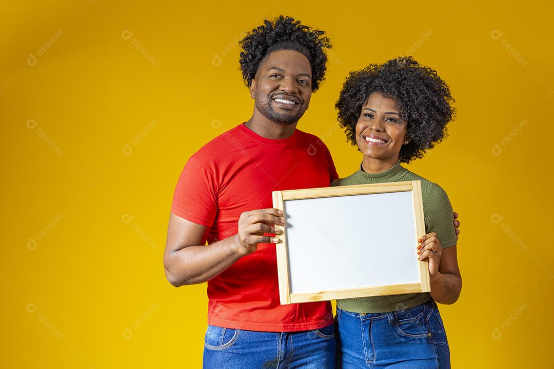 Casal Afro com cabelo afro e roupa de festa junina segurando Papelão