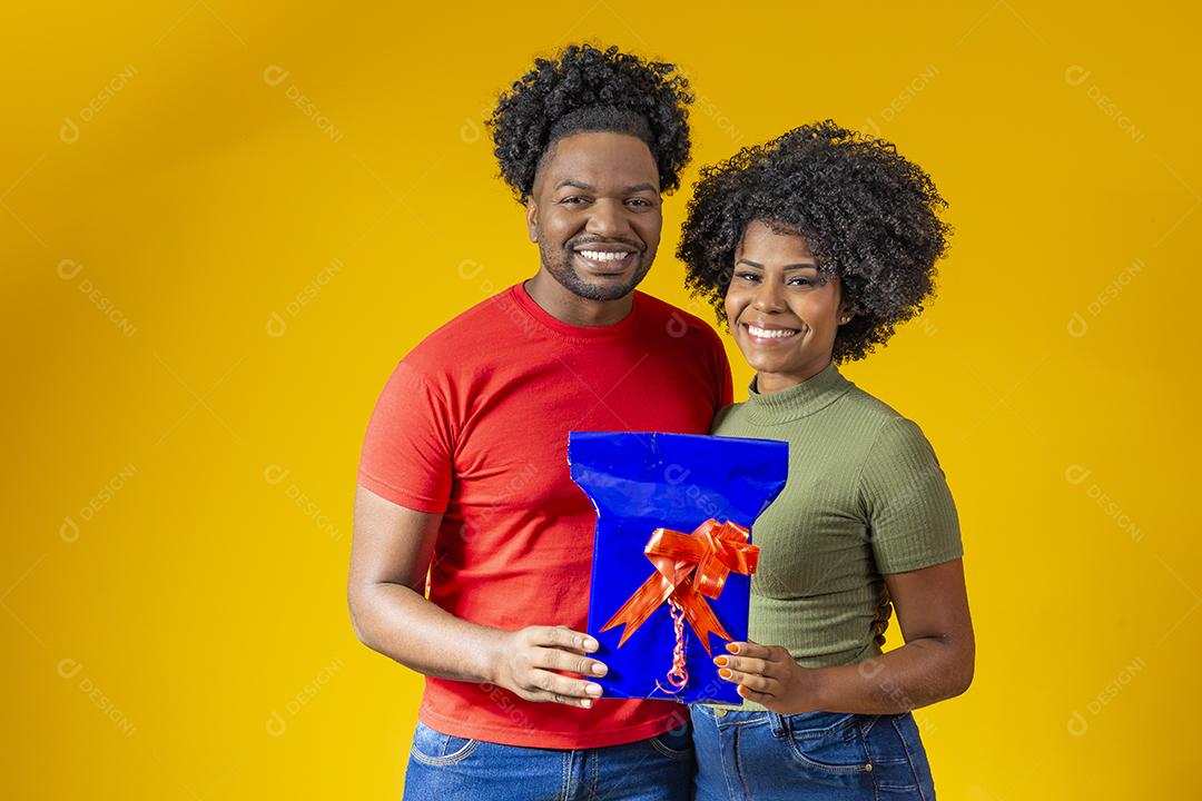 Casal afro em fundo amarelo com um presente