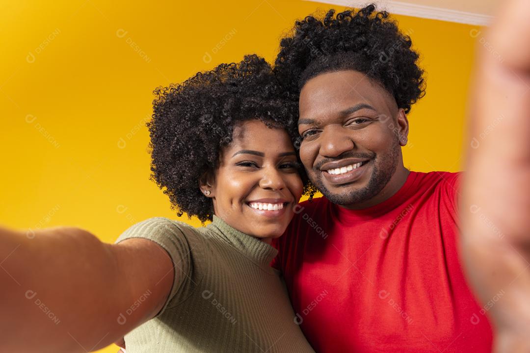 casal negro tirando uma selfie em fundo amarelo