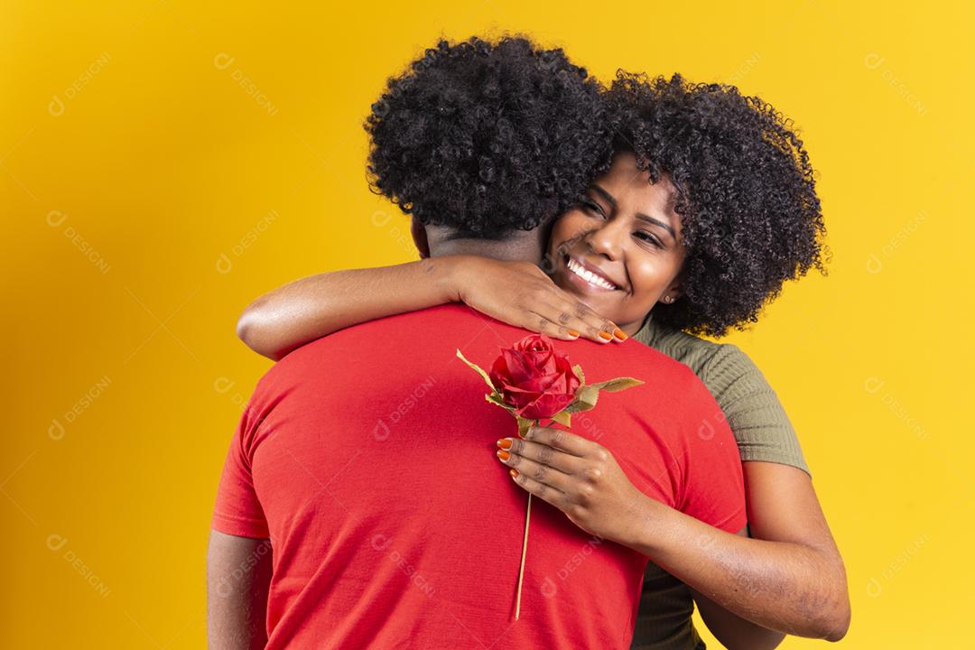 casal negro abraçando em fundo amarelo e mulher segurando uma flor