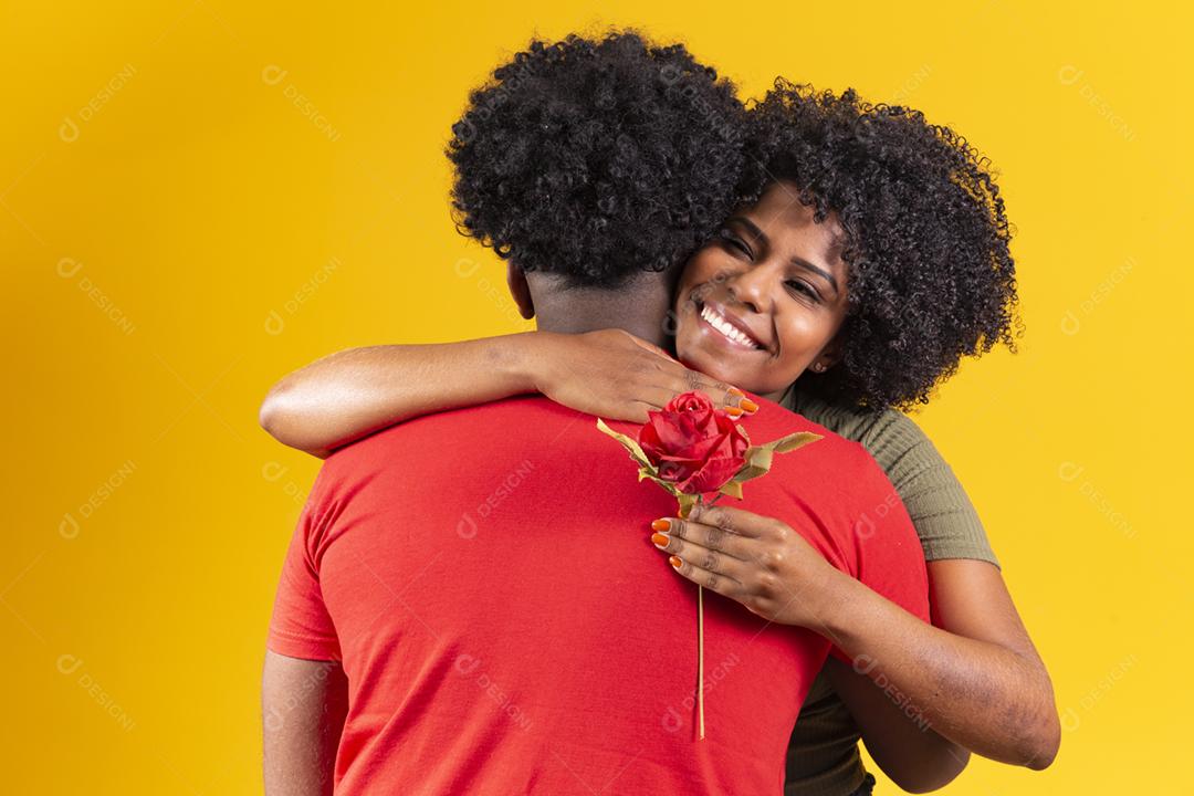 casal negro abraçando em fundo amarelo e mulher segurando uma flor