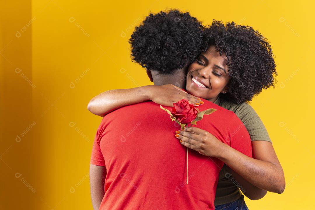 casal negro abraçando em fundo amarelo e mulher segurando uma flor