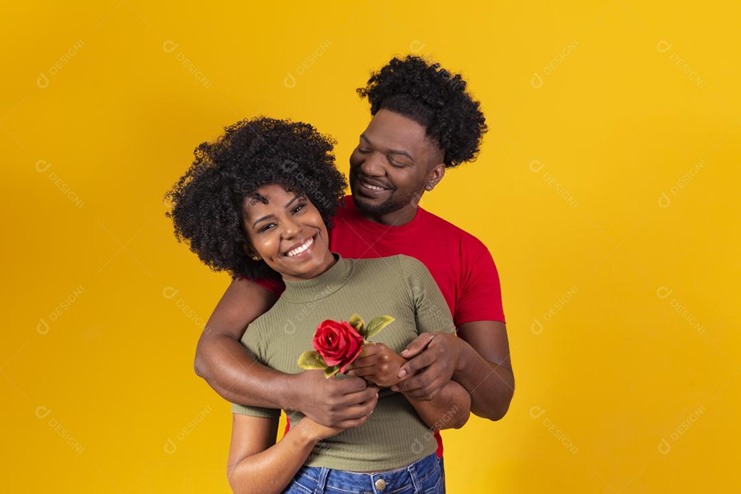 casal negro abraçando em fundo amarelo e mulher segurando uma flor