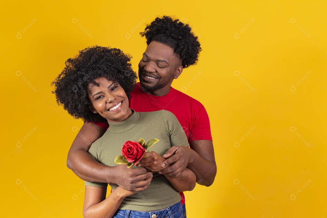 casal negro abraçando em fundo amarelo e mulher segurando uma flor