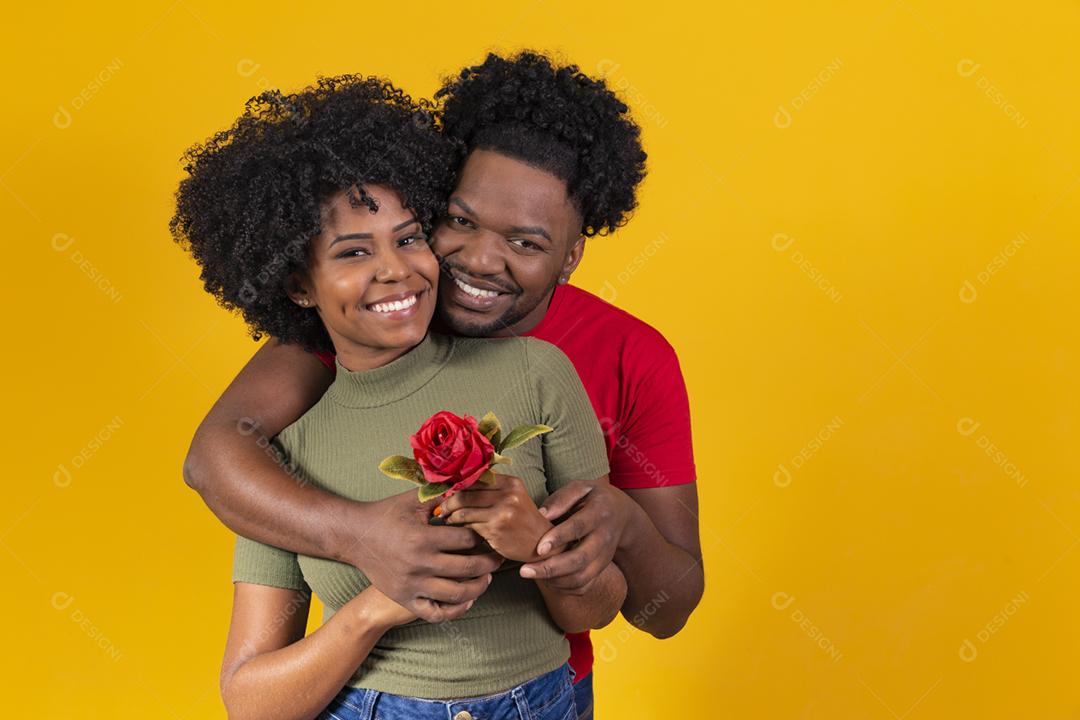 casal negro abraçando em fundo amarelo e mulher segurando uma flor