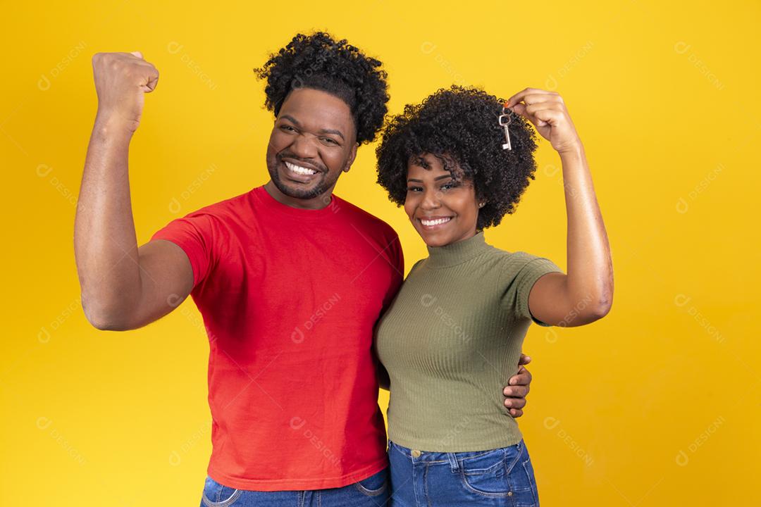 casal de namorados em fundo amarelo, segurando a chave da casa.