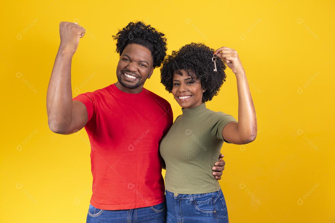 loving couple on yellow background holding house key.
