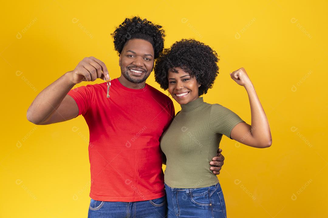 casal de namorados em fundo amarelo, segurando a chave da casa.