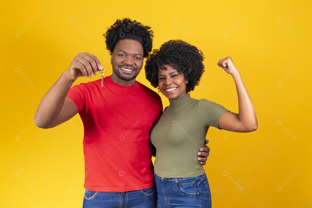 casal de namorados em fundo amarelo, segurando a chave da casa.