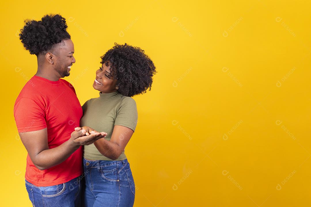 Casal negro apaixonado dançando em fundo amarelo com espaço livre
