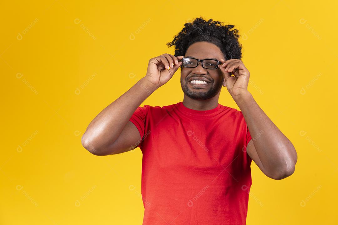 Homem afro com óculos em fundo amarelo sorrindo com a mao no oculos