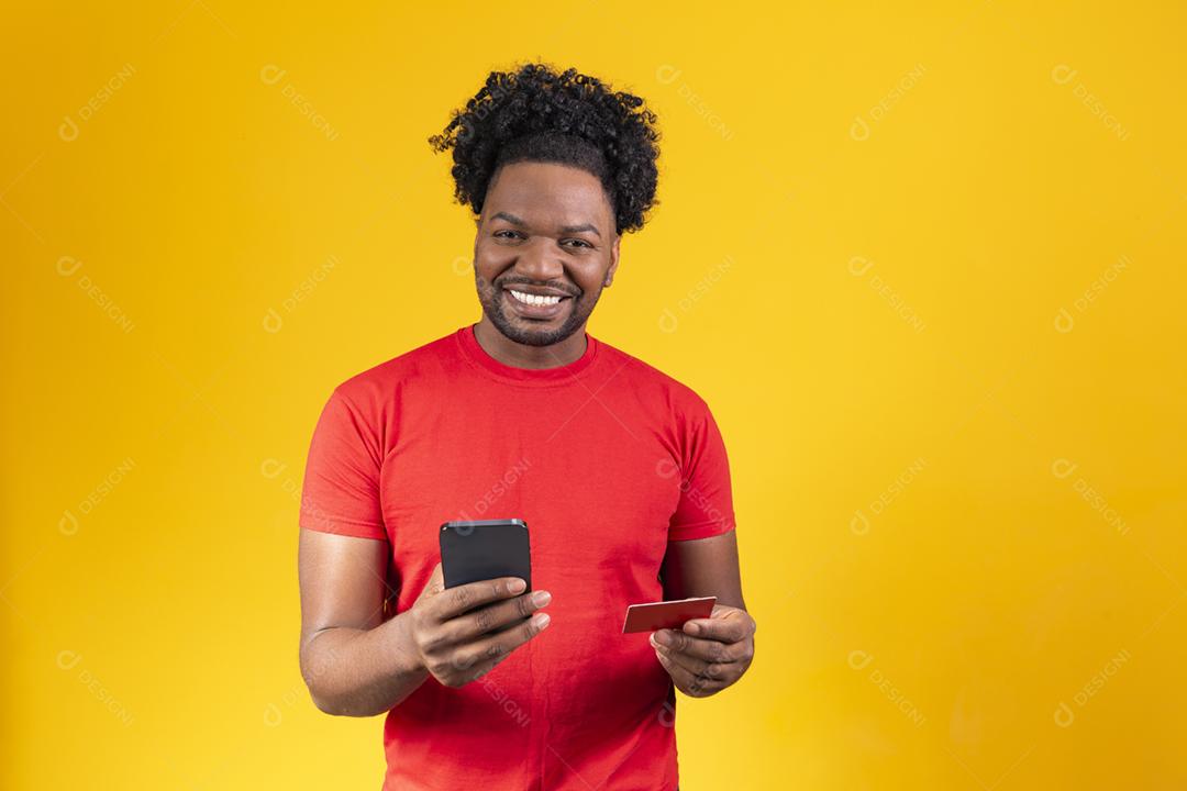 Alegre jovem afro segurando novo celular e um cartão de crédito
